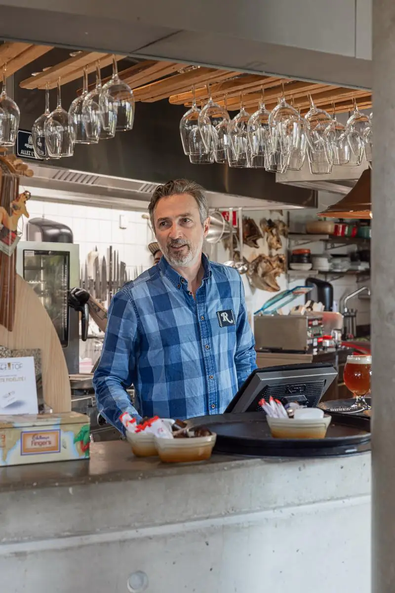 Derrière le bar, sous les verres suspendus